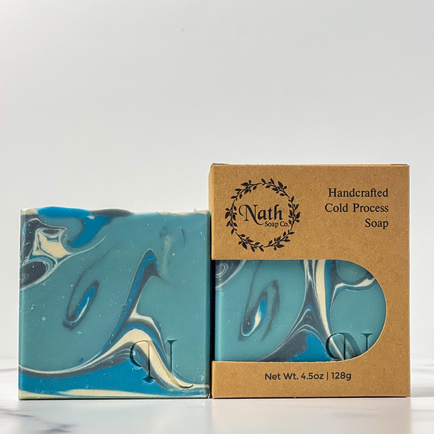 2 blue, black and white and soaps, one packaged in a kraft colored box, one without box