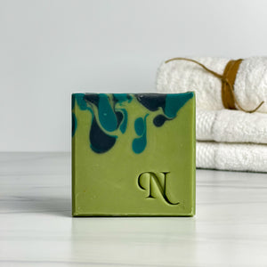 Awake Artisan Soap - one green and black soap with white folded towels in the background