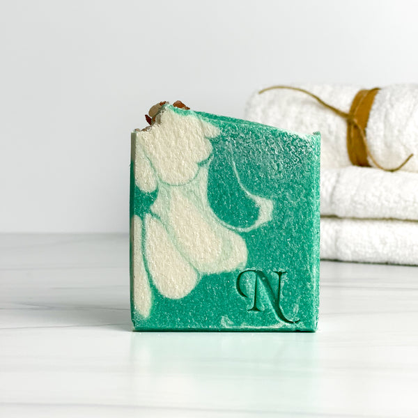 Aura Salt Soap - one teal green and white soap with folded white towels in the background